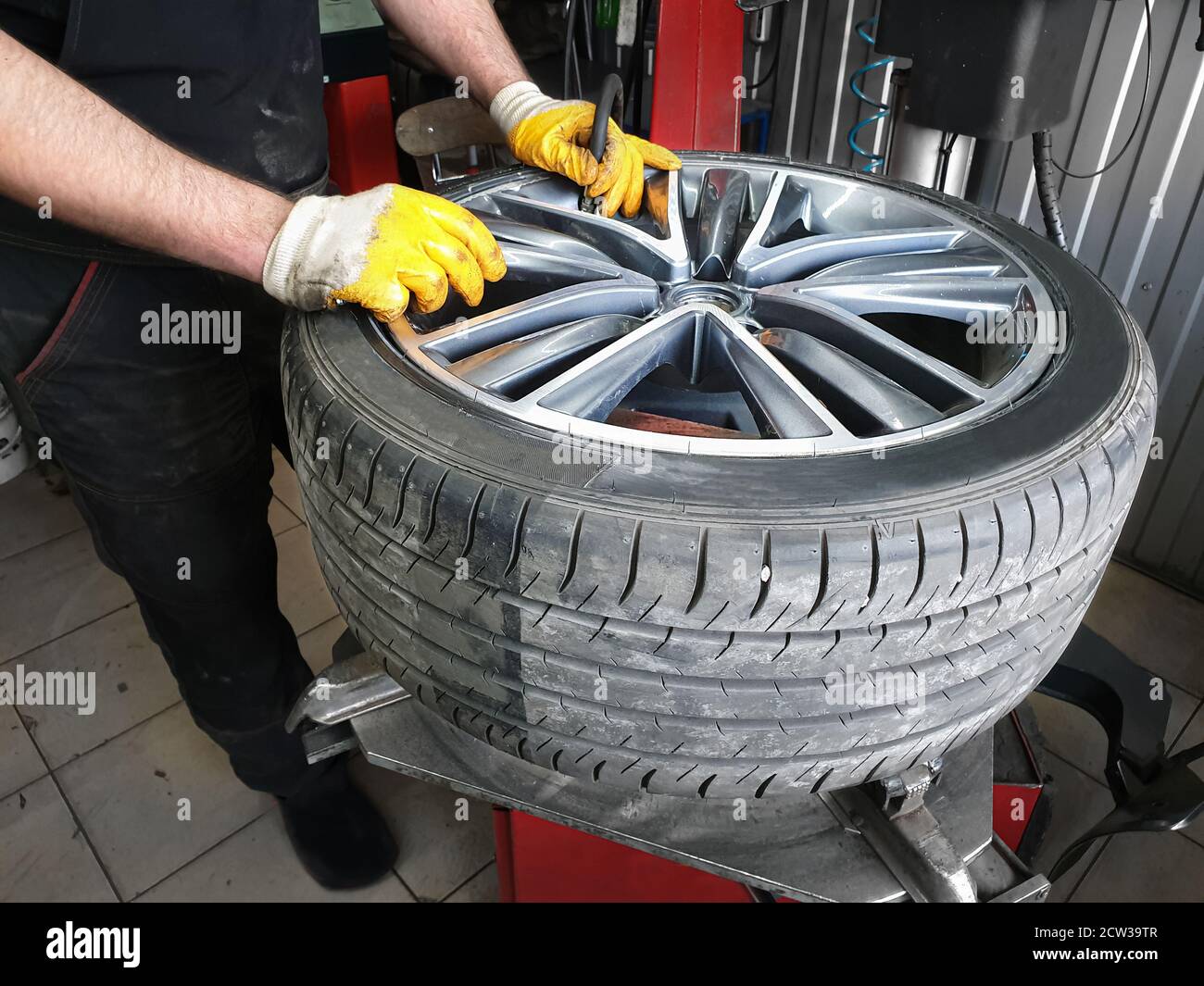 Reifenservice... Die Hände des Automechanikers, der ein Rad mit dem Reifen hält. Mechaniker bläst das Rad durch den Nippel auf Stockfoto