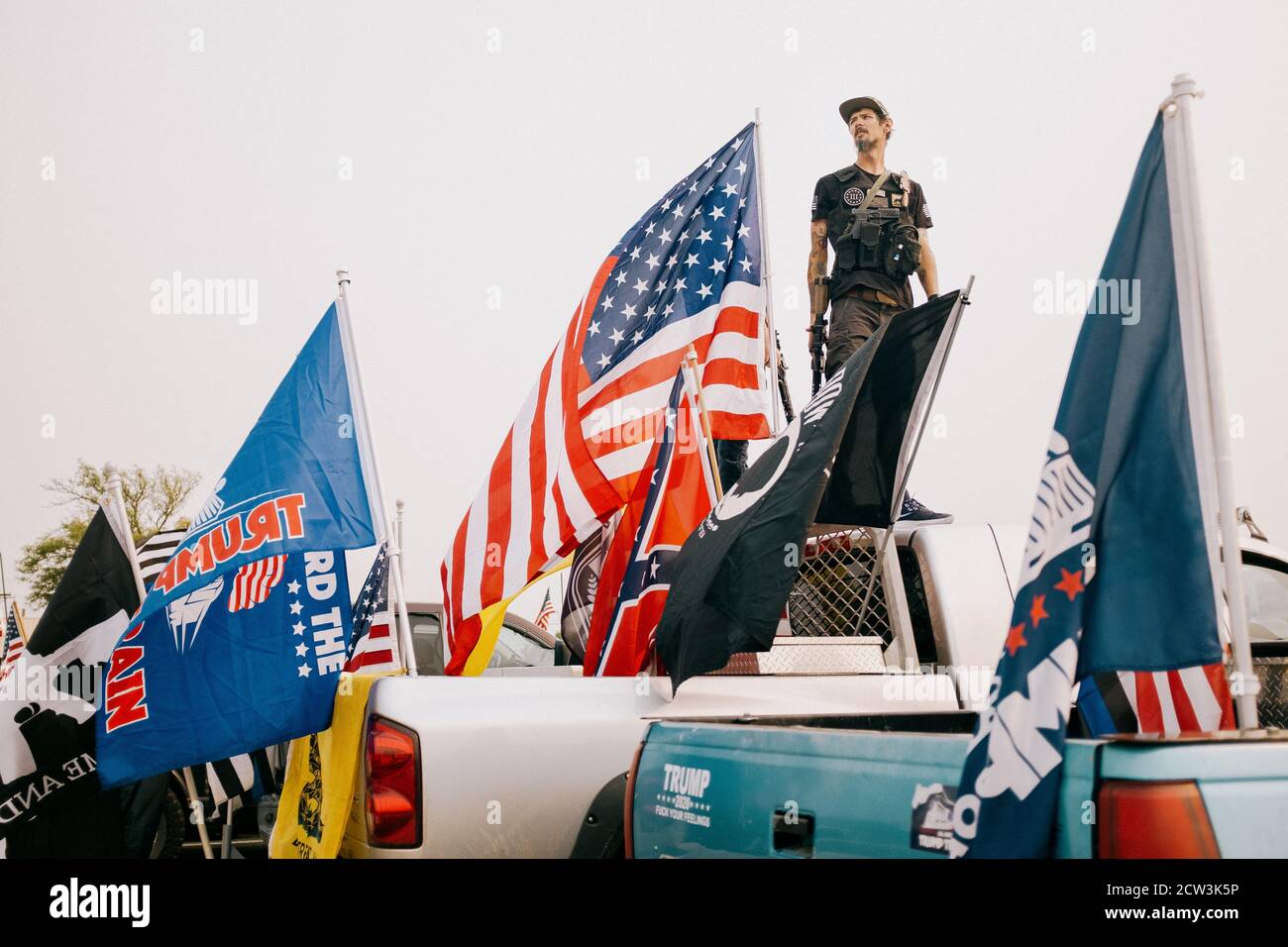 Ein Trump 2020-Anhänger steht auf der Rückseite seines Pickup-Trucks, der Trump 2020 und Q-Anon Flaggen fliegt. Stockfoto