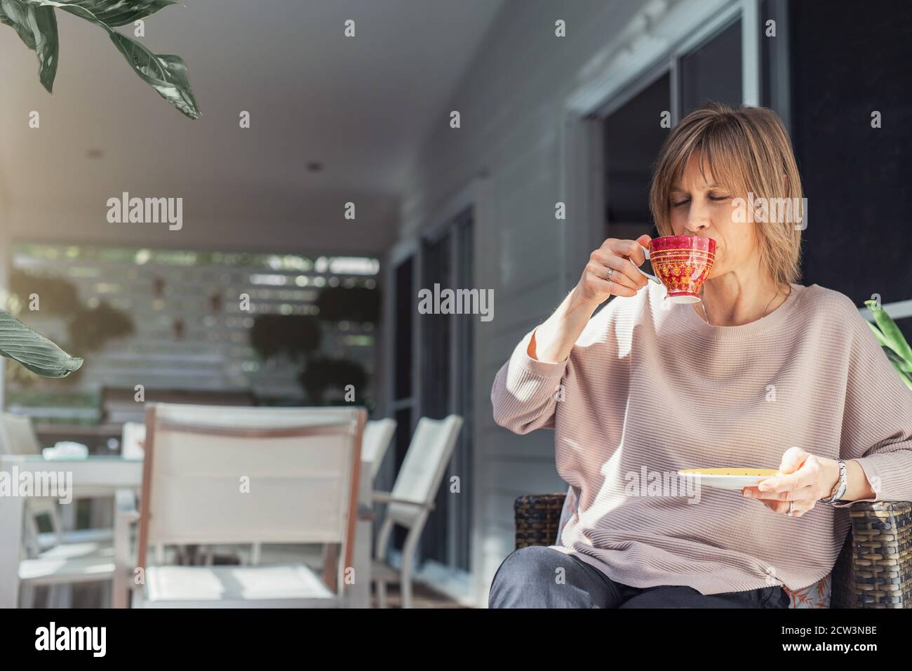 Frau mittleren Alters trinkt Kaffee oder Tee auf dem Balkon genießen. Stockfoto