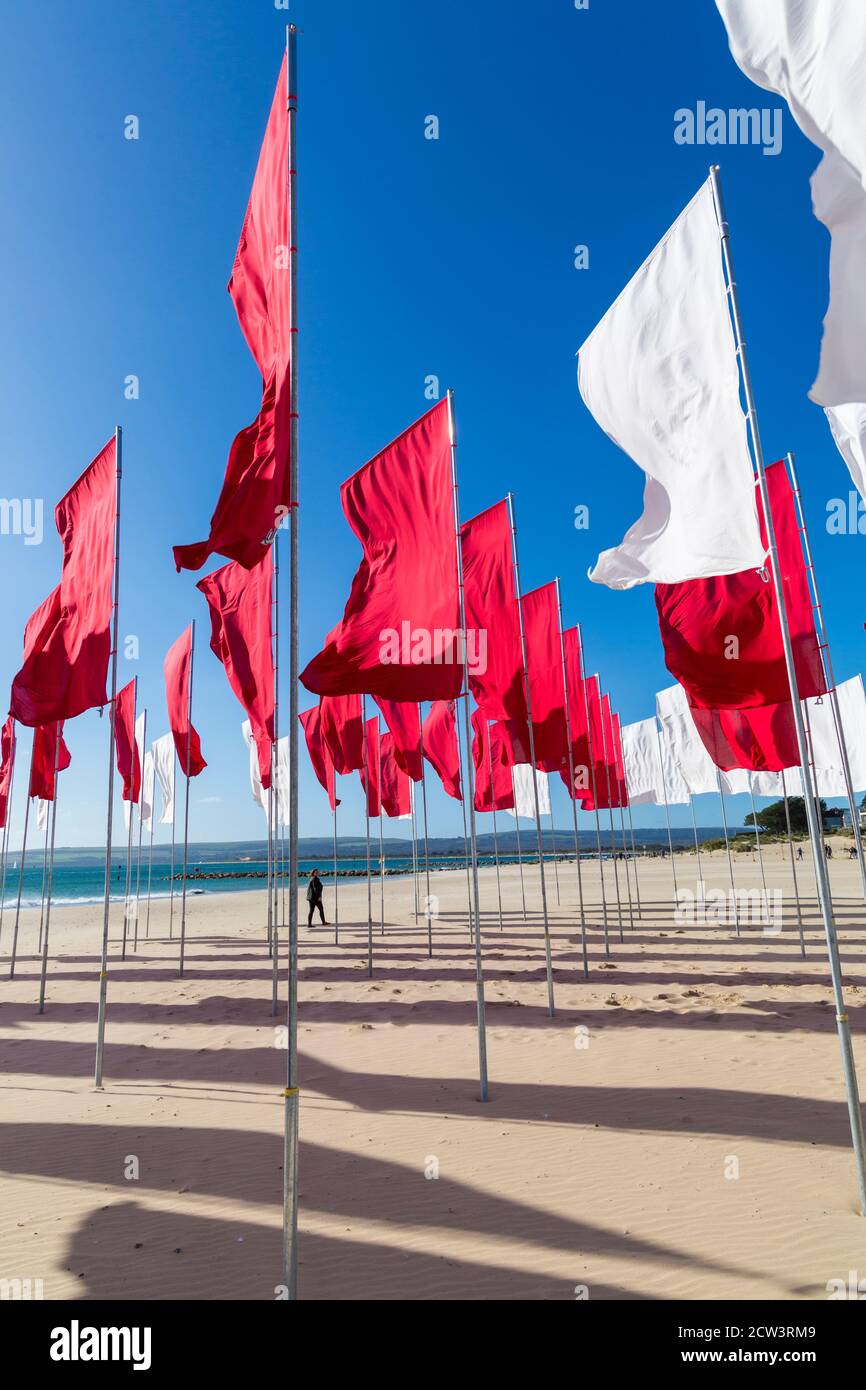 Sandbanks, Poole, Dorset, Großbritannien. September 2020. Die Menschen besuchen Luke Jerrams Kunstwerk "in Memoriam" am Strand von Sandbanks, das aus über 100 Bettlaken, einem riesigen Meer von Flaggen, geschaffen wurde, um an die Verlorenen von Covid-19 zu erinnern – Teil des Bournemouth Arts by the Sea Festivals. Die Installation ist in Form eines medizinischen Logos, eines roten Kreuzes auf weißem Hintergrund angeordnet und würdigt auch die mutigen Mitarbeiter und Freiwilligen des NHS, die weiterhin ihr Leben riskieren, um die Tausenden von Menschen zu versorgen, die vom Coronavirus betroffen sind. Quelle: Carolyn Jenkins/Alamy Live News Stockfoto