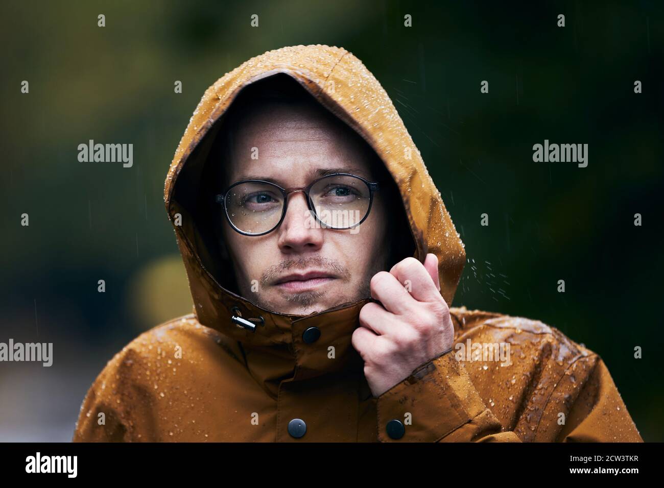 Starker Regen während des Herbsttages. Porträt des jungen Mannes in wasserdichter Jacke. Stockfoto