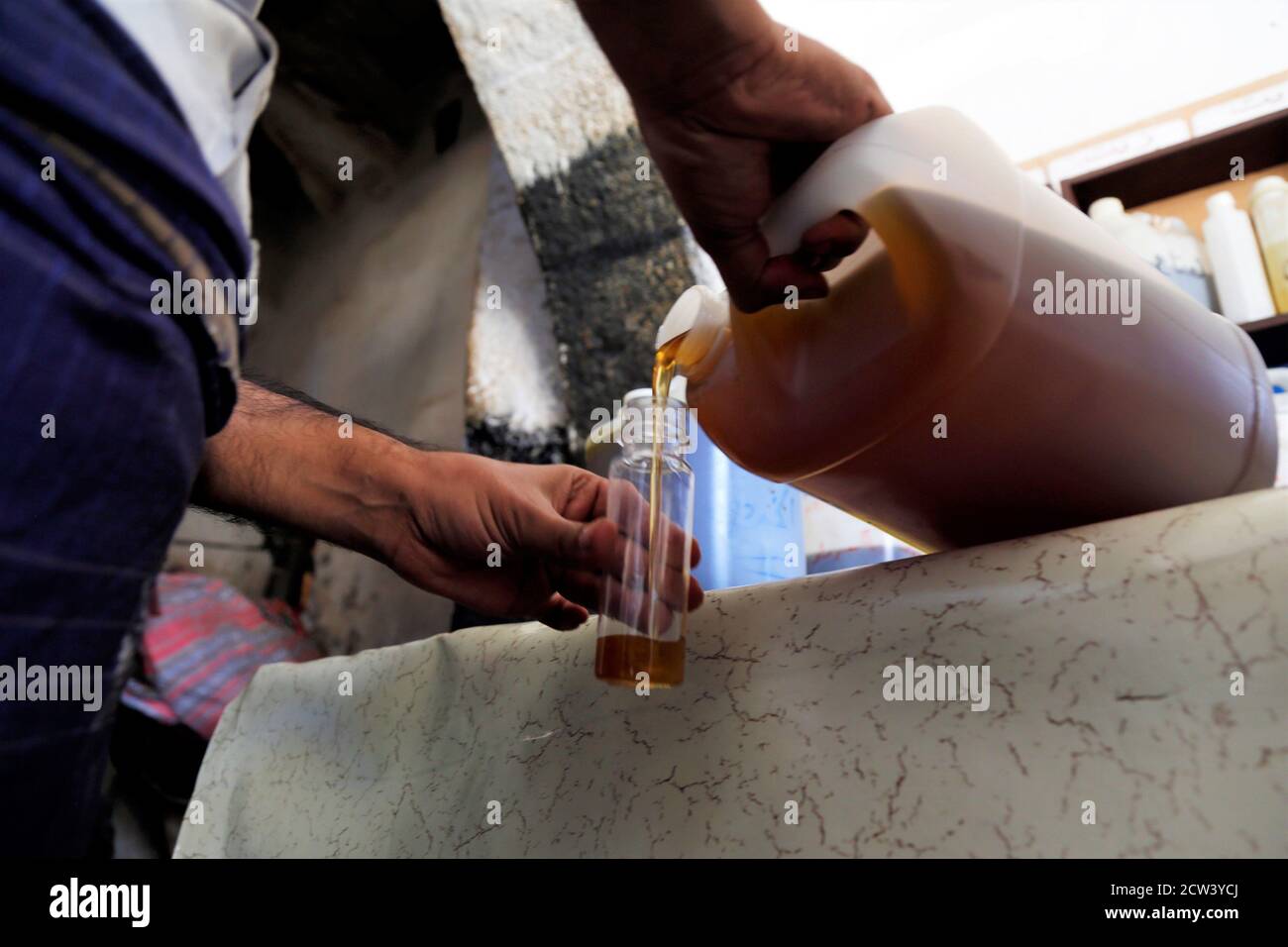 (200927) -- SANAA, 27. September 2020 (Xinhua) -- EIN Mann gießt Sesamöl in eine Flasche für einen Kunden in einer Ölmühle in Sanaa, Jemen, 27. September 2020. (Foto von Mohammed Mohammed/Xinhua) Stockfoto