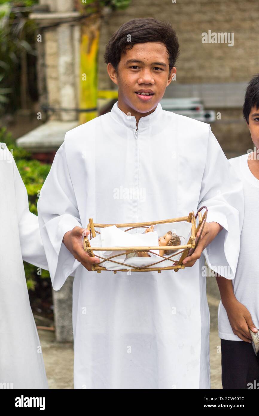 Ein Bild des Jesuskindes wird von einem Sakristan gehalten. Sein Gefolge besucht während der Weihnachtszeit katholische Häuser Stockfoto