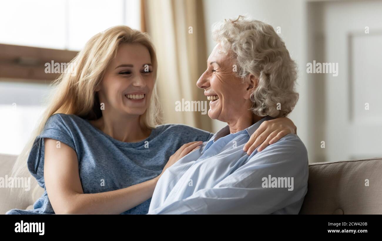 Glücklich erwachsen Enkelkind umarmend Schultern der geliebten Großmutter Stockfoto