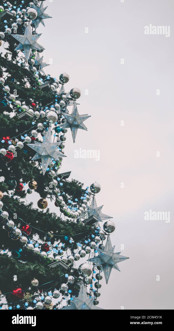 Nahaufnahme von großen Weihnachtsbaum mit verschiedenen weihnachtsspielzeug und dekorative Verzierungen auf der Straße. Nadelbaum mit Girlande, Perlen und Sternen Stockfoto