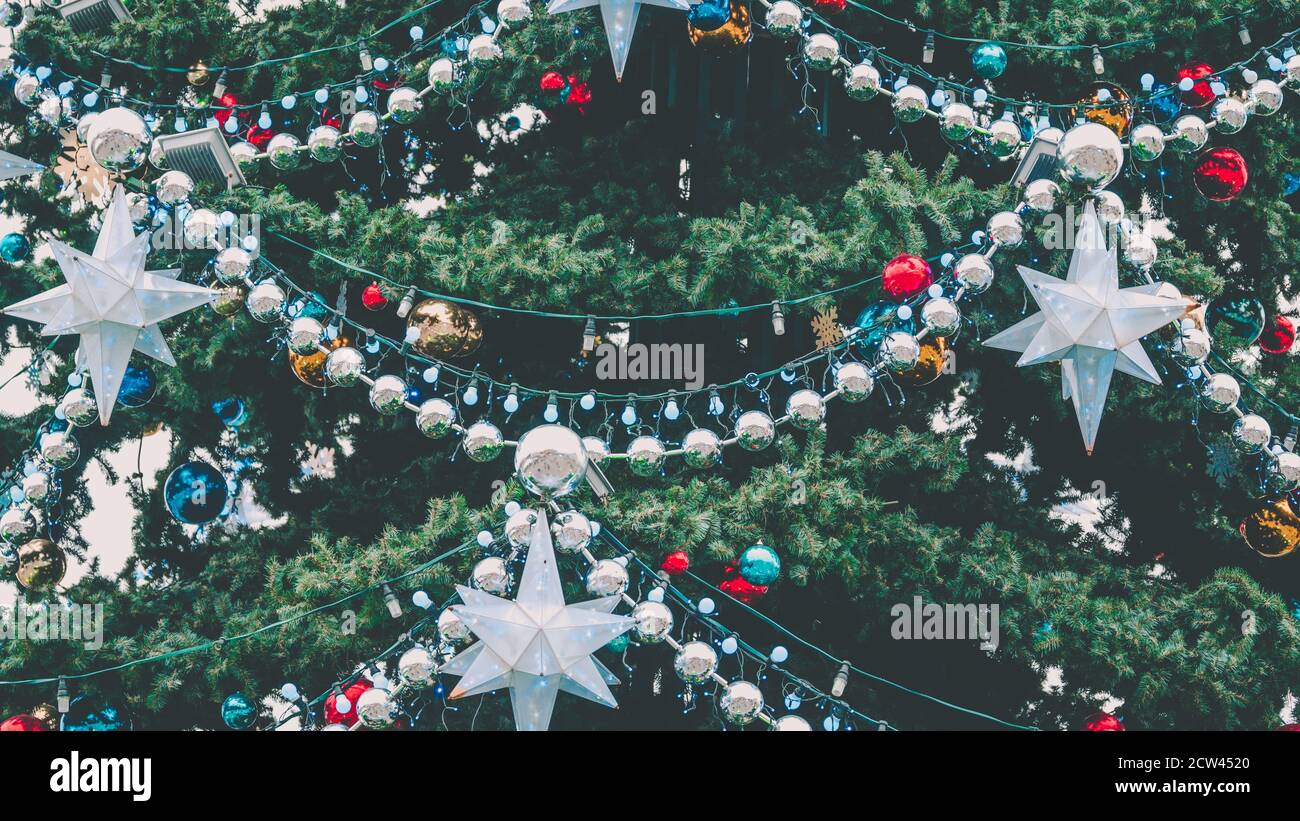 Nahaufnahme von großen Weihnachtsbaum mit verschiedenen weihnachtsspielzeug und dekorative Verzierungen auf der Straße. Nadelbaum mit Girlande, Perlen und Sternen Stockfoto