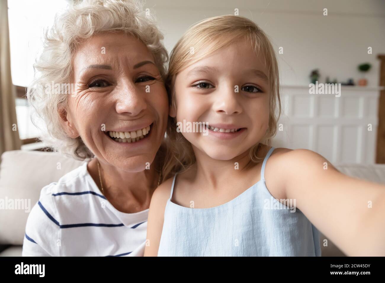 Kleines Mädchen sitzt auf Runden von älteren Großmutter machen Selfie Stockfoto