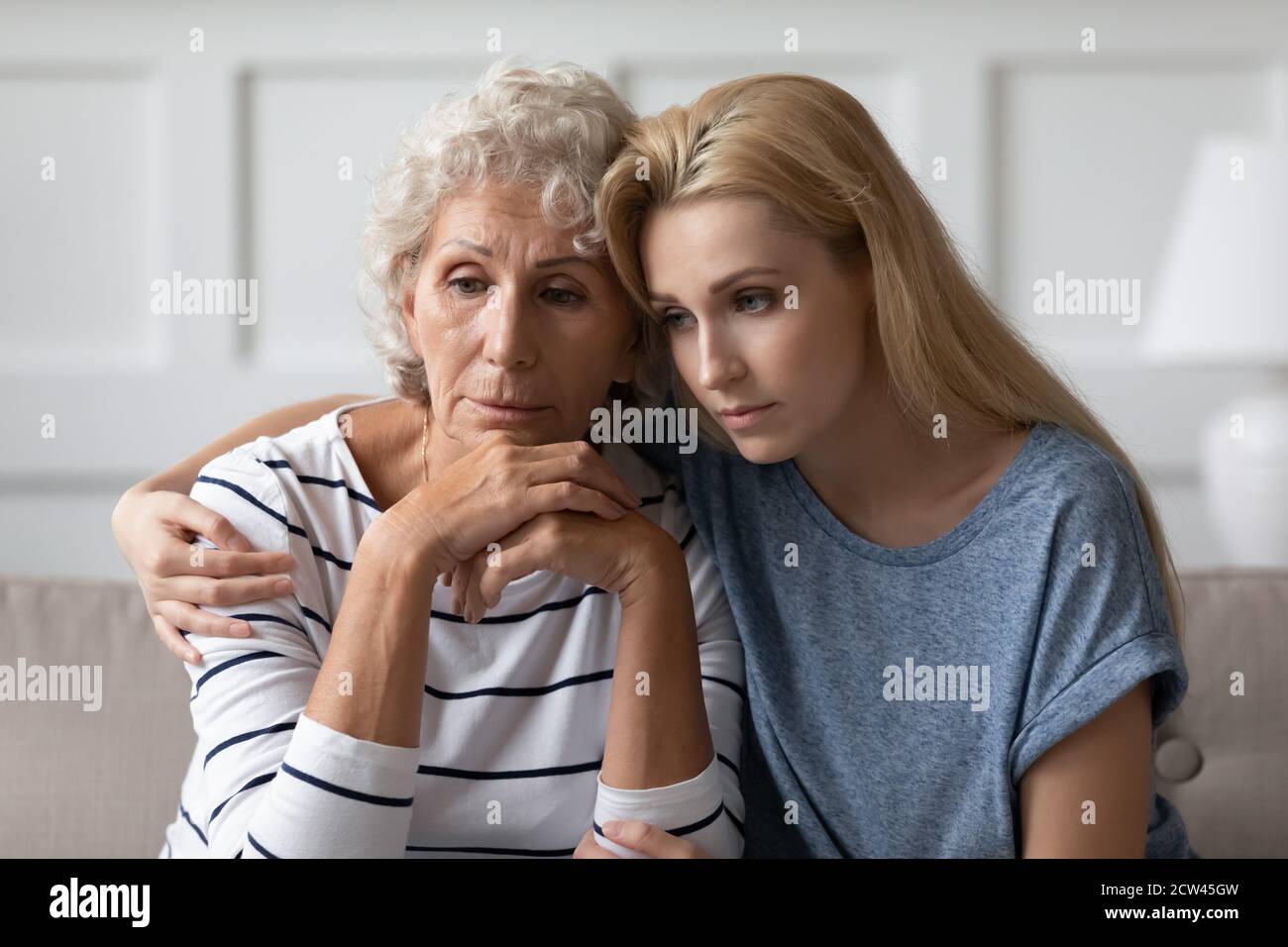 Traurige Erwachsene Tochter sitzt auf dem Sofa umarmt verzweifelte ältere Mutter Stockfoto