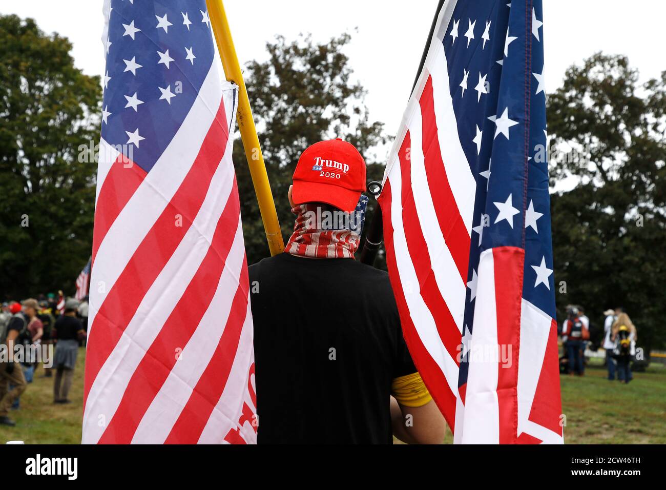 Während der Demonstration im Delta Park hält ein Protestler Flaggen.Mitglieder der rechtsextremen Proud Boys - einige mit Schusswaffen und Körperpanzerung - massierten bei einer Kundgebung in Portland, Oregon, während sich in der Nähe Gegenkundgebungen abzeichneten und Beamte in der angespannten Stadt sich auf Gewalt einschalteten. Stockfoto