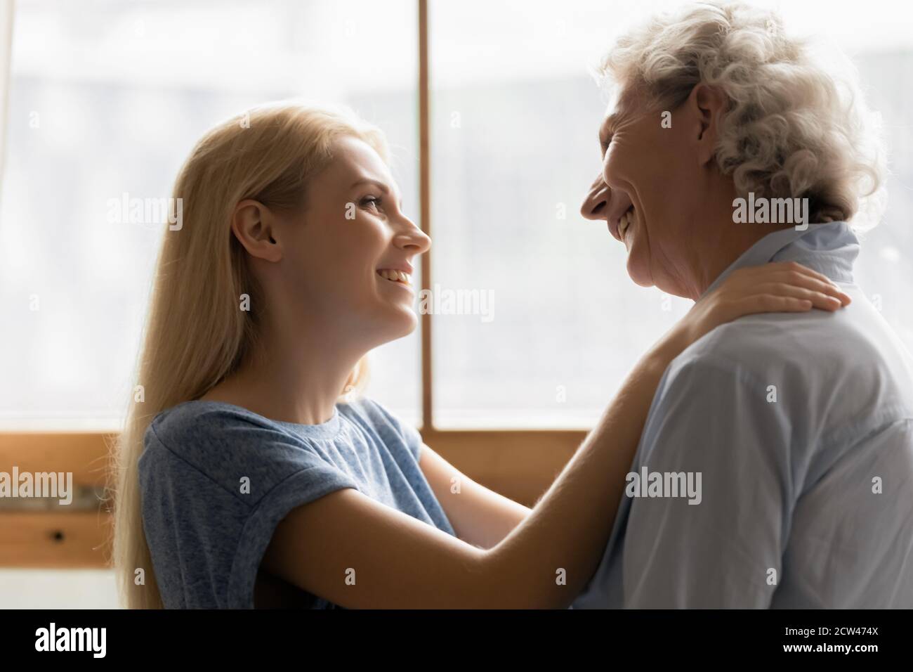 Anhänglich junge Tochter umarmt sanft silberhaarige ältere Mutter Stockfoto