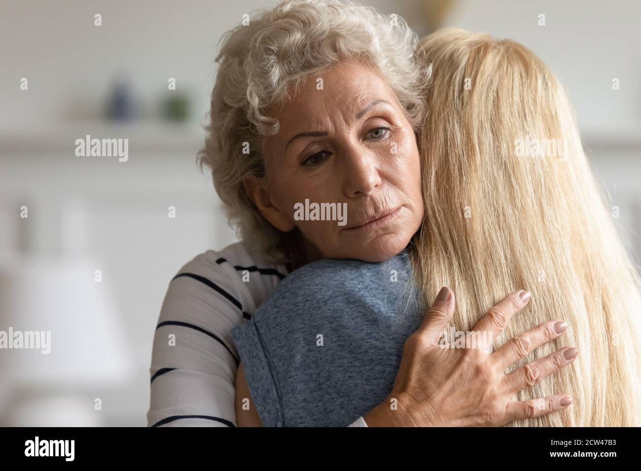 Fürsorgliche alte Mutter umarmt Erwachsene Tochter mit Mitgefühl in den Augen Stockfoto