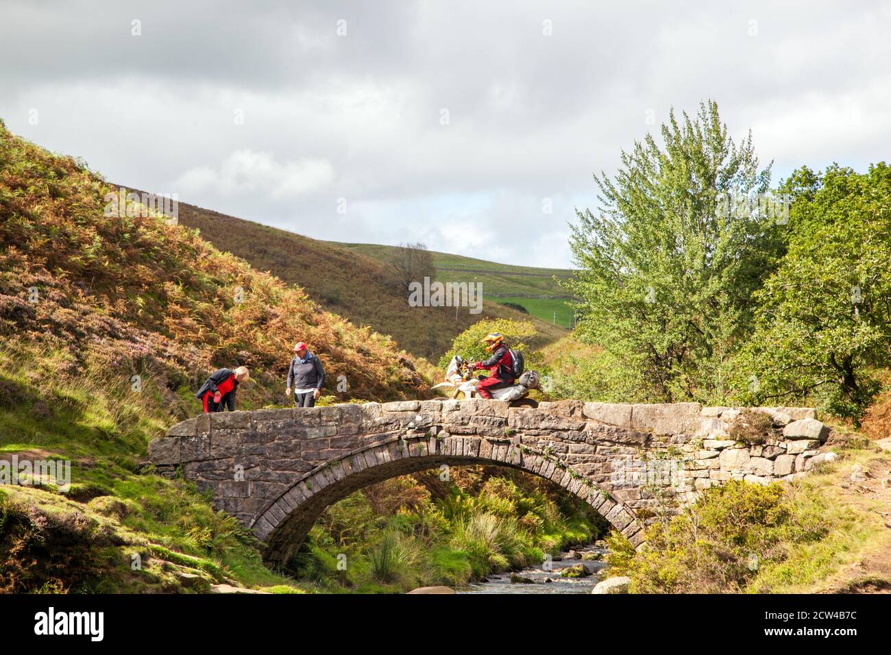 Off-Road-Motorradfahrer mit einer grünen Spur Weg überqueren die Steinbrücke an den drei Shires Kopf in der Spitze District National Park England Großbritannien Stockfoto