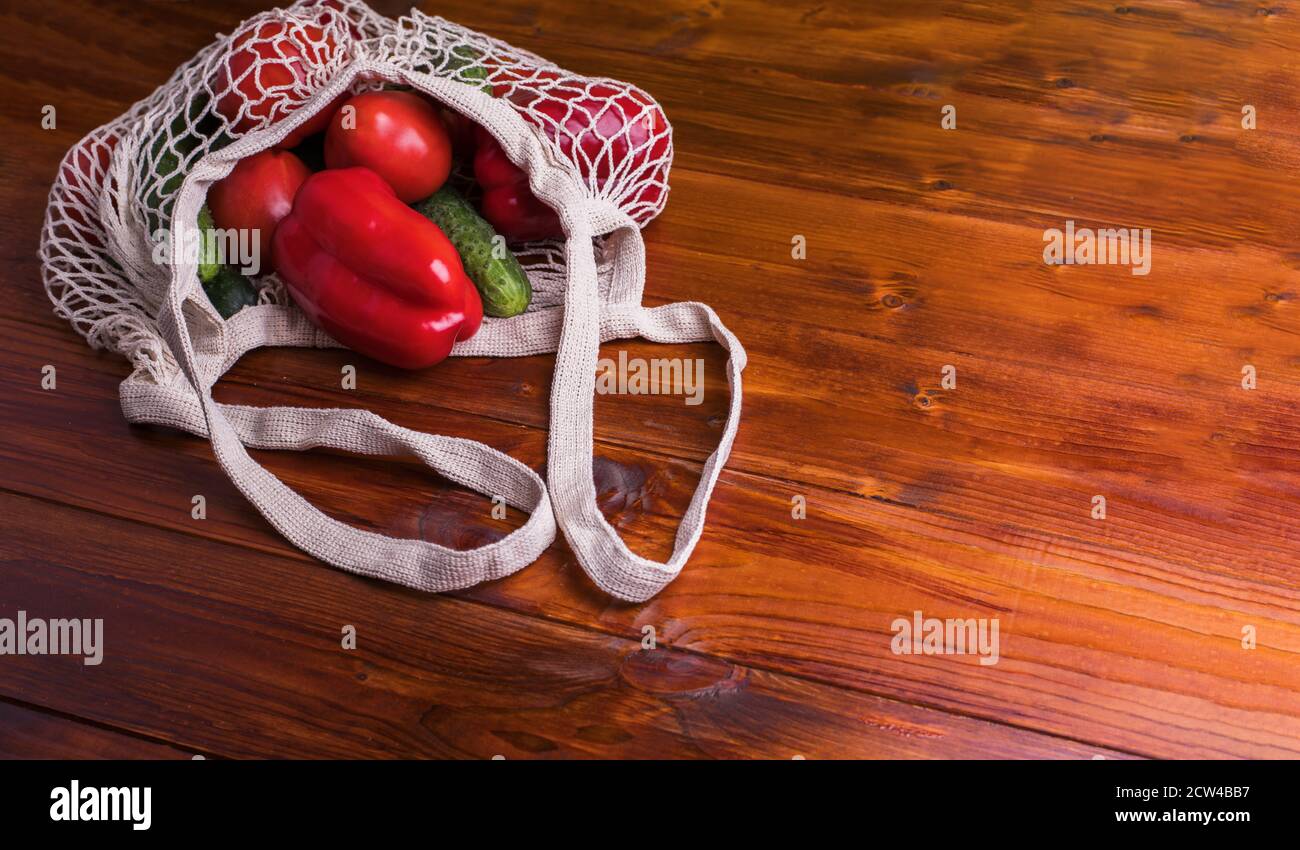 Eco Beutel Saite Beutel mit Gemüse Gurken und Tomaten auf einem Holzhintergrund. Zero West Flat Lay, Draufsicht Stockfoto