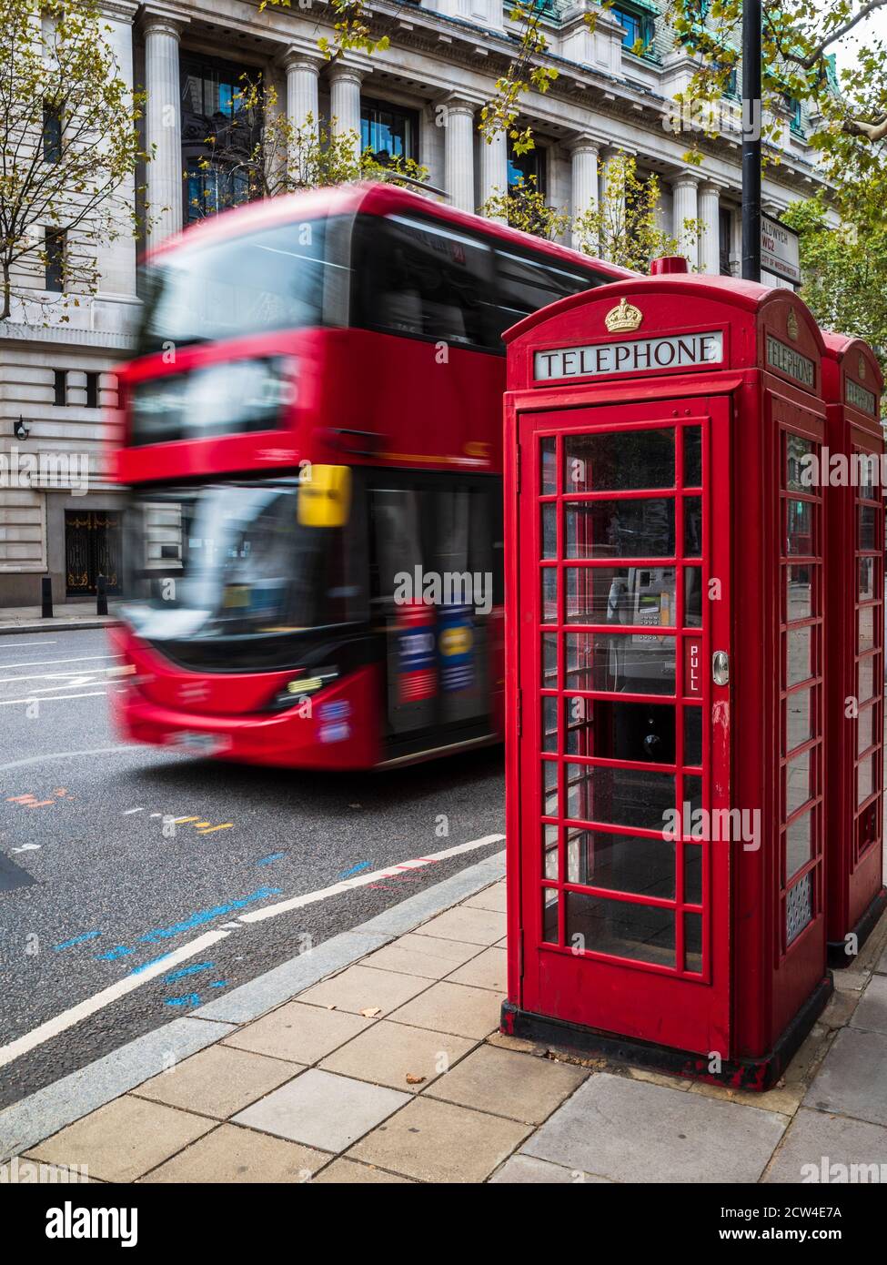 Ikonisches London - ein roter Bus fährt an zwei traditionellen roten Telefonzellen im Zentrum von London vorbei. Bewegungsunschärfe der Busbewegung. London Tourism. Stockfoto