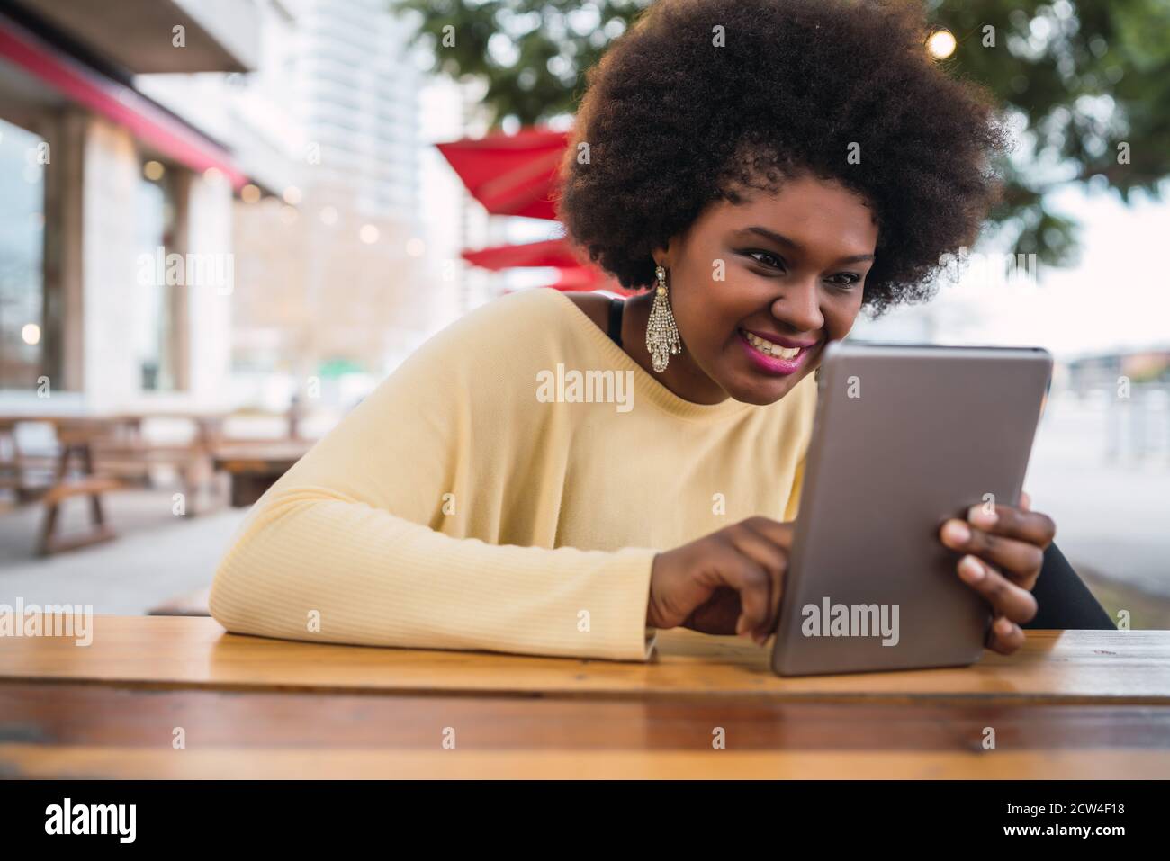 Porträt einer jungen afroamerikanischen lateinerin, die ihr digitales Tablet benutzt, während sie im Café sitzt. Technologiekonzept. Stockfoto