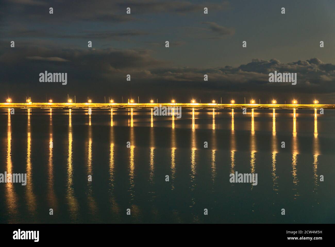 Wunderschöne Hafenlaternen Beleuchtung am Abend. Reflexion des Lichts im Wasser. East Pier von Dun Laoghaire Hafen während der blauen Stunde, Dublin Stockfoto