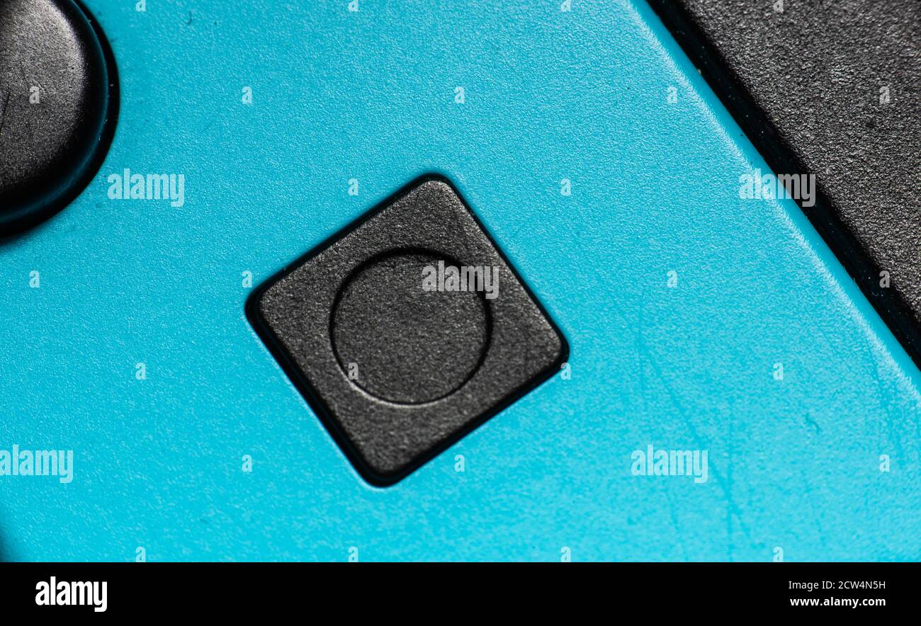 Eine schwarze quadratische Taste auf einem blauen Handregler Stockfoto