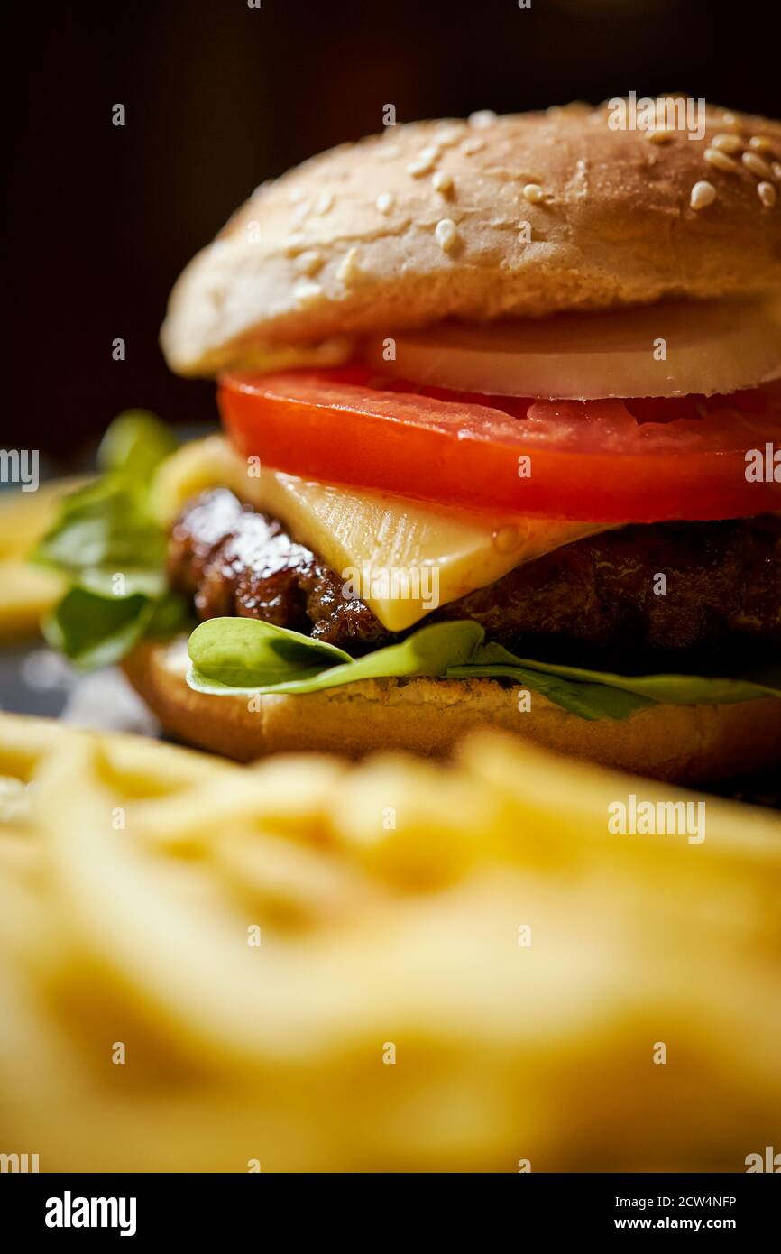 Cheeseburger umgeben von pommes auf einem schwarzen Tisch Stockfoto