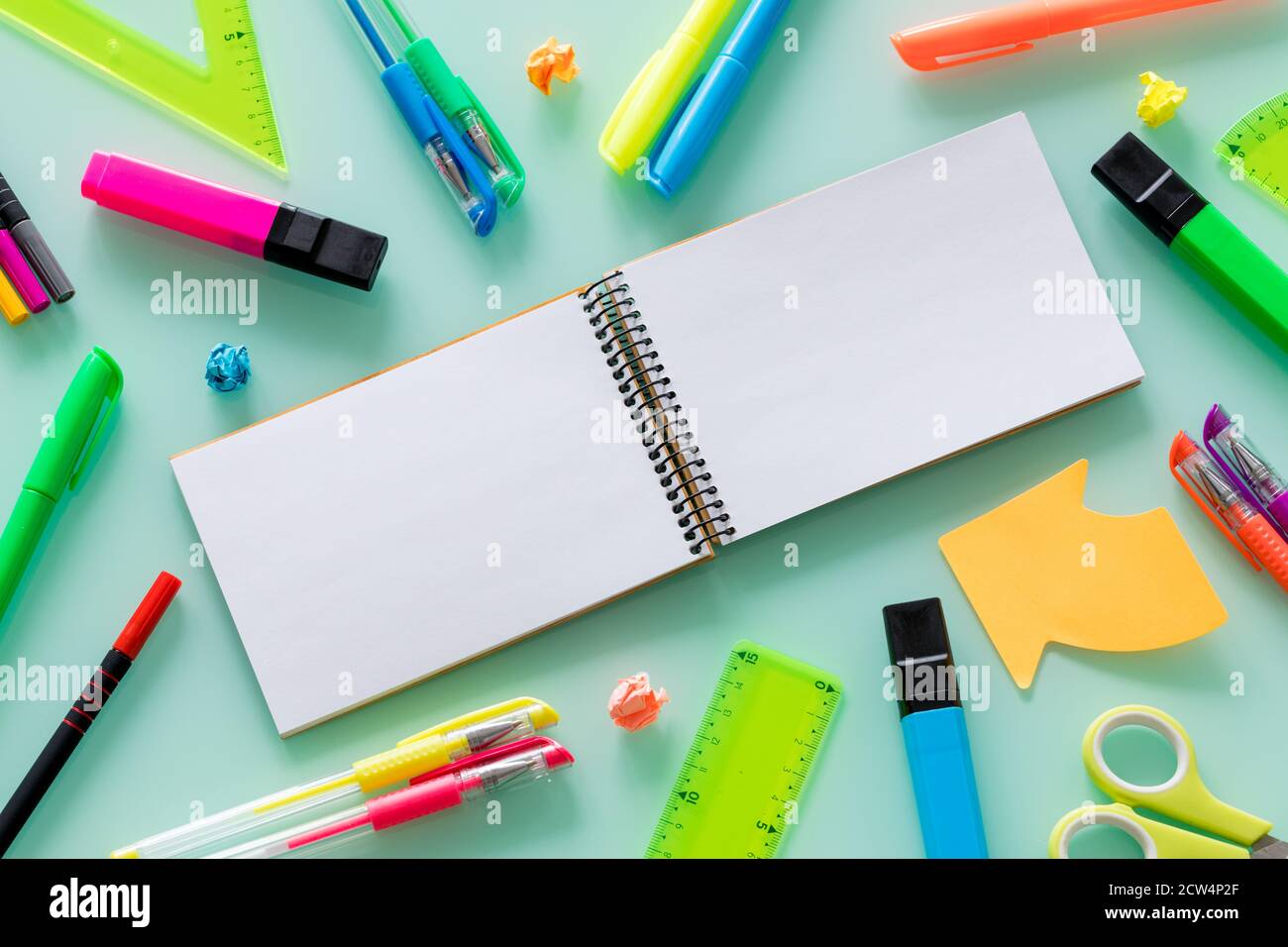 Schul- und Büroartikel, farbige Stifte, Heftklammern, Filzstifte, Set Quadrate, ein leeres Notizbuch für den eigenen Text in der Mitte. Stockfoto