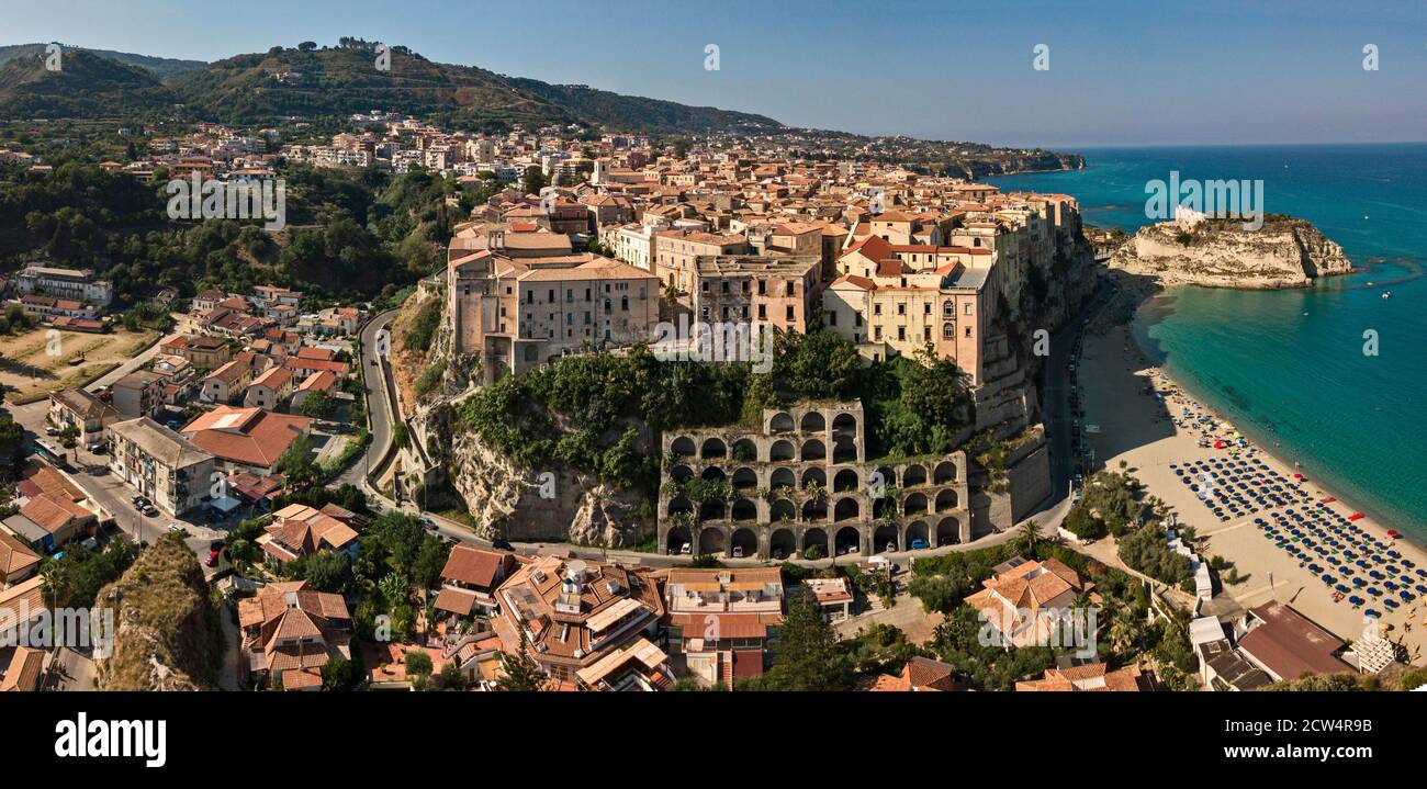 Luftaufnahme des Strandes mit Sonnenschirmen und Badegäste. Häuser auf dem Felsen. Vorgebirge des Heiligtums von Santa Maria dell'Isola, Tropea, Kalabrien, Italien Stockfoto