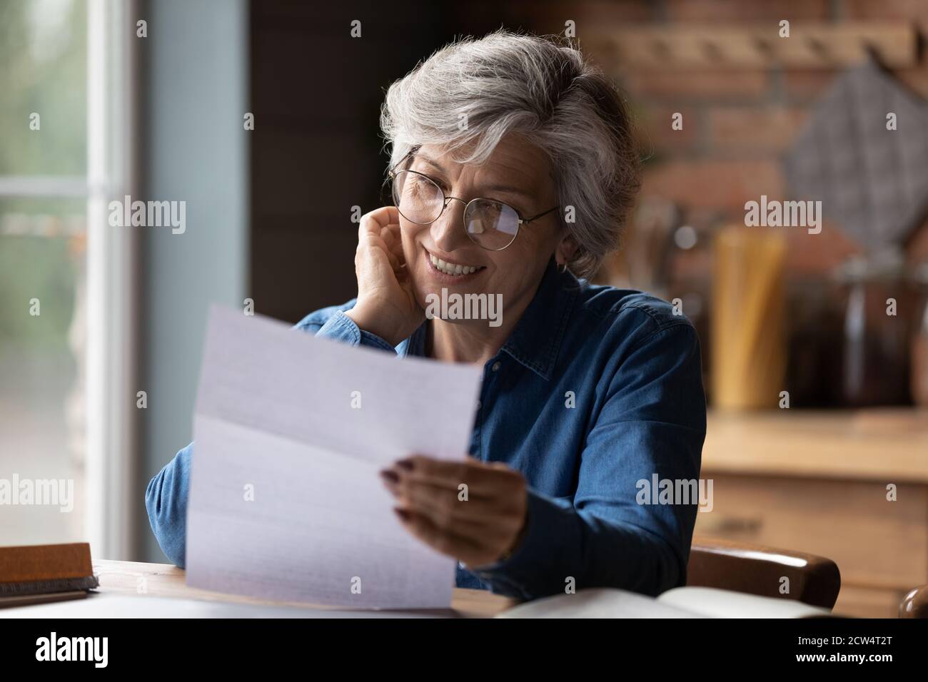 Reife 60s Frau lesen Papier Postkorrespondenz zu Hause Stockfoto