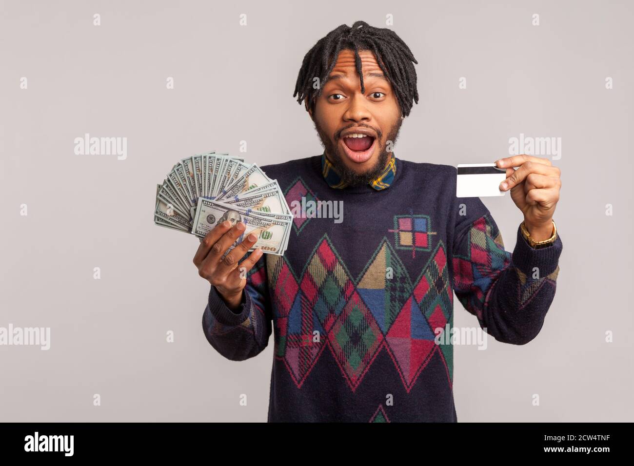 Aufgeregt schockiert afrikanischen Mann mit Dreadlocks halten in den Händen Stapel von Dollar und Kreditkarte Blick auf die Kamera, überrascht mit Kredit, Kaution. Zoll Stockfoto
