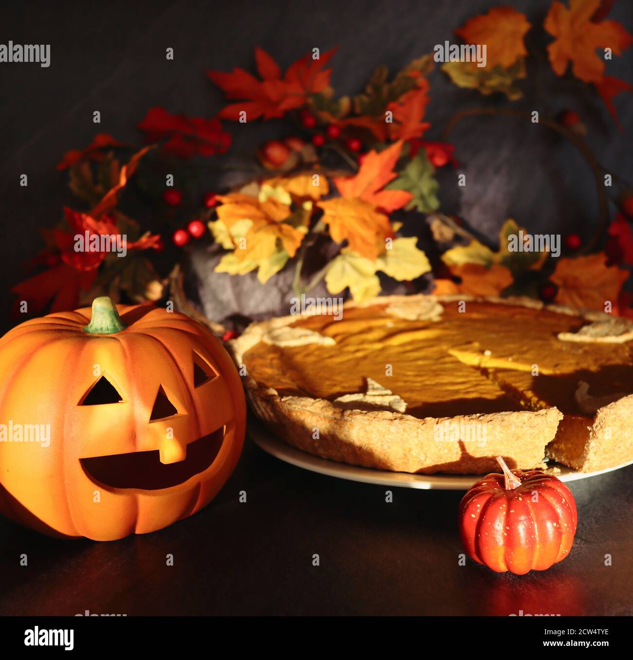 Halloween Kürbis mit glutenfreien Kürbis Pie während Sonnentag erschossen. Herbst Vibes mit Nahrung und künstlichem Kürbis und Blättern. Stockfoto