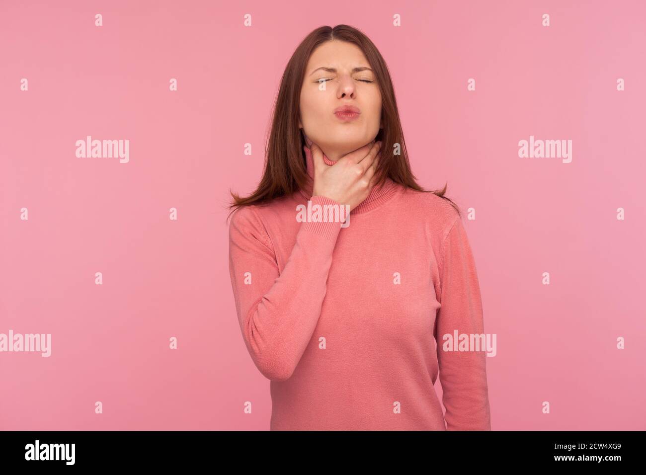 Traurige Frau mit braunen Haaren tastenden Hals Gefühl Kehlschmerzen und Schmerzen während der Schwalbe, Mandelentzündung Entzündung. Innenaufnahme des Studios isoliert auf pinkem Rücken Stockfoto