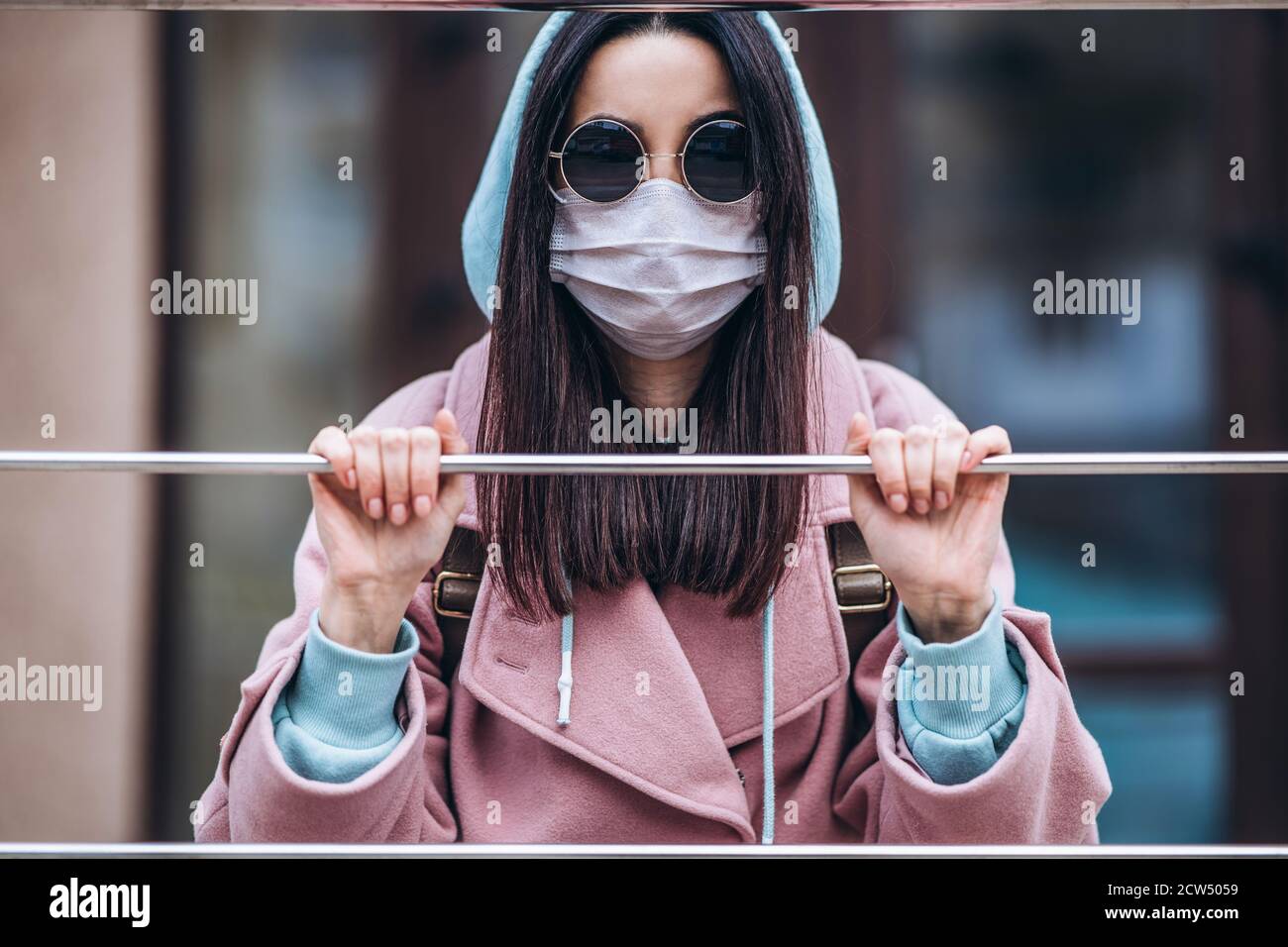 Frau in medizinischer Maske im Freien hinter dem Tor. Gesundheitsschutz und Prävention von Virus, Coronavirus, COVID-19, Epidemie und Pandemie, infektiöse d Stockfoto