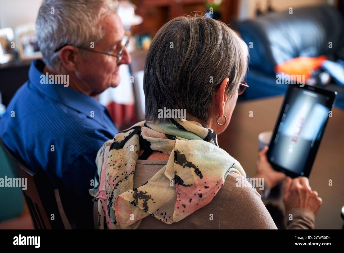 Rückansicht Des Älteren Ehepaars Zu Hause, Das Videoanruf Macht Zur Familie Oder Zum Ansehen Von Filmen Auf Einem Digitalen Tablet Stockfoto
