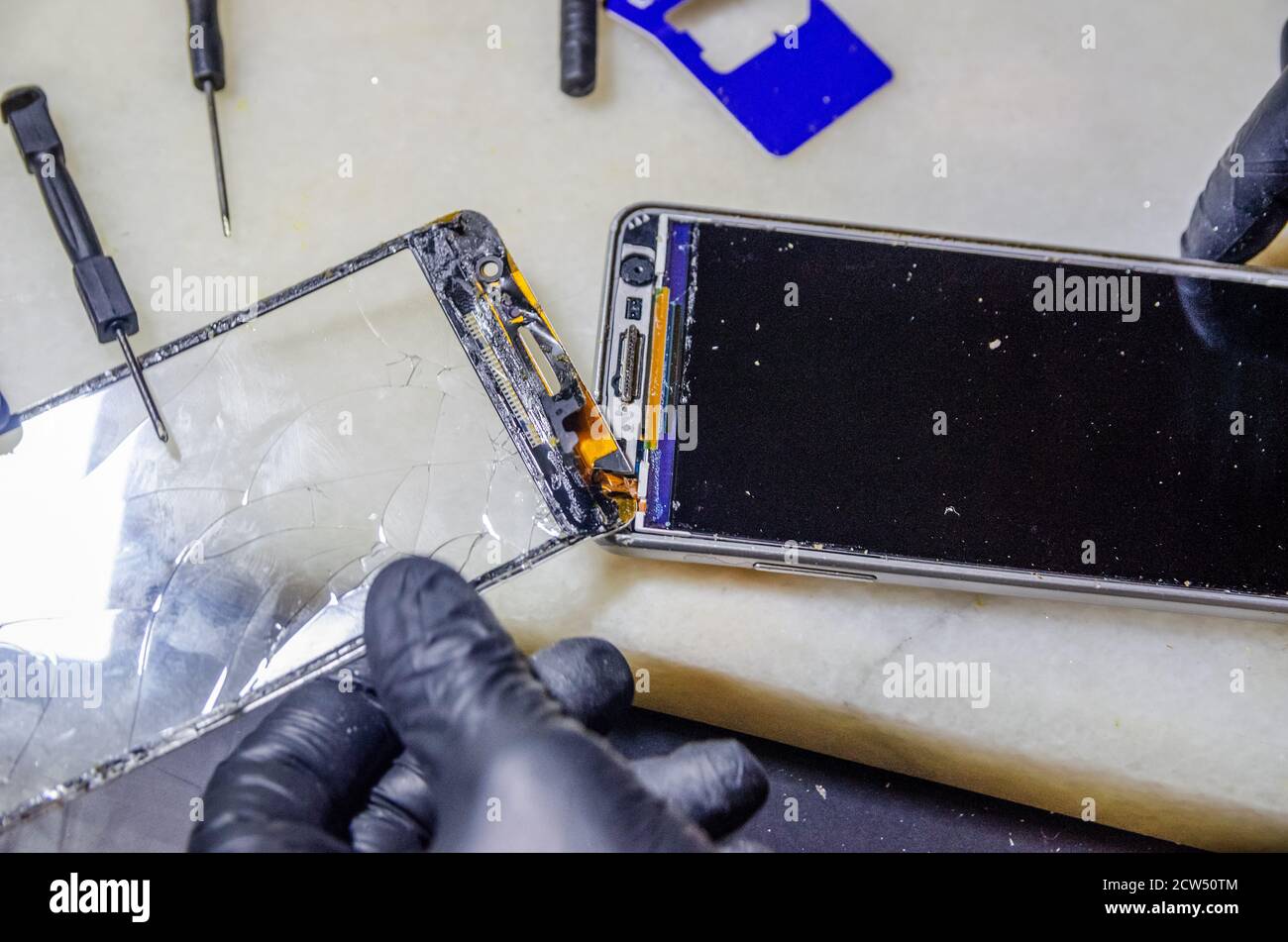 Spezialist ersetzt einen geknackten Bildschirm auf einem weißen Smartphone Nahaufnahme Stockfoto