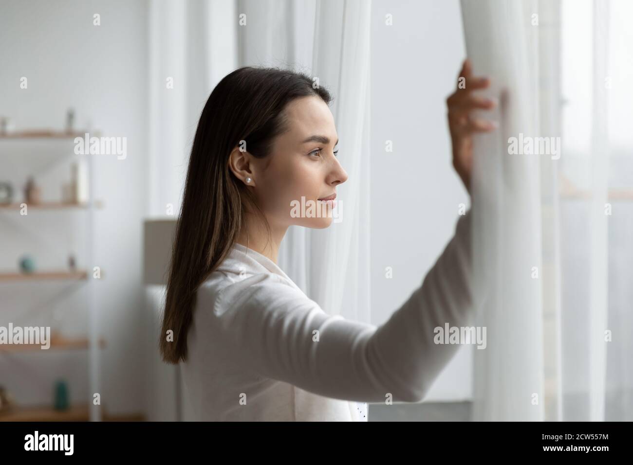 Junge Frau offene Vorhänge Blick in der Ferne in eigenen Hause Stockfoto