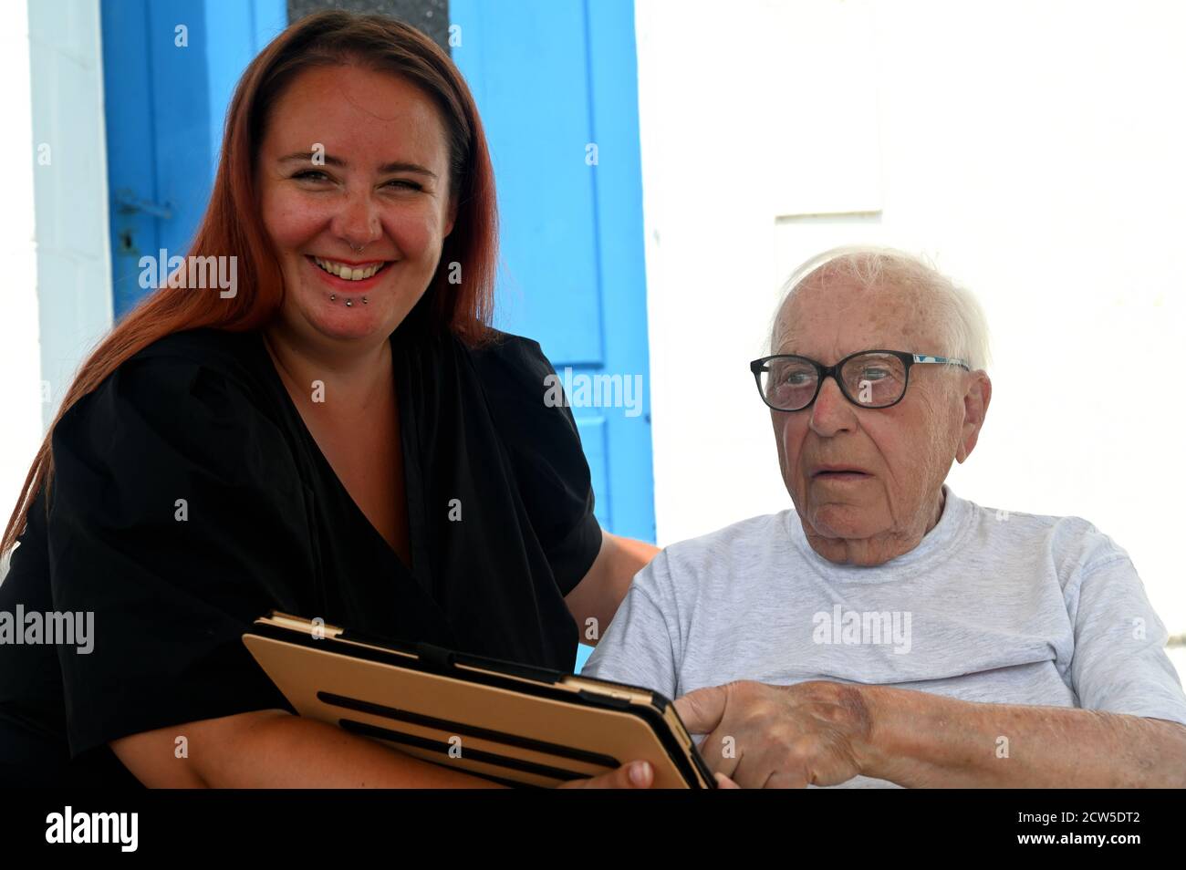 Junge Frau mit einem alten Mann, der einen digitalen Blick hat Tablet Stockfoto