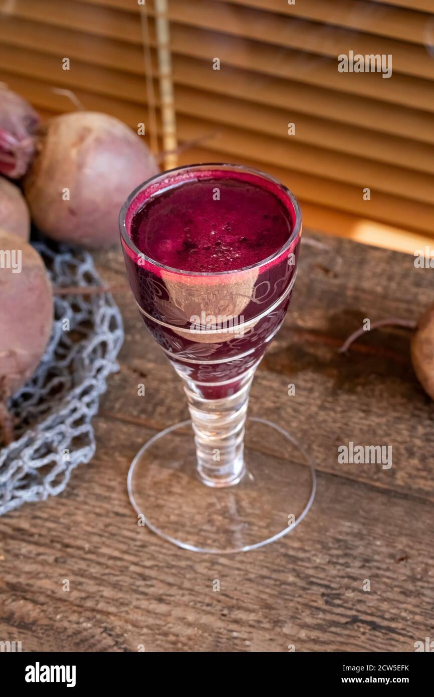 Roter Rübensaft in einem Glas mit frischen Wurzeln Stockfoto