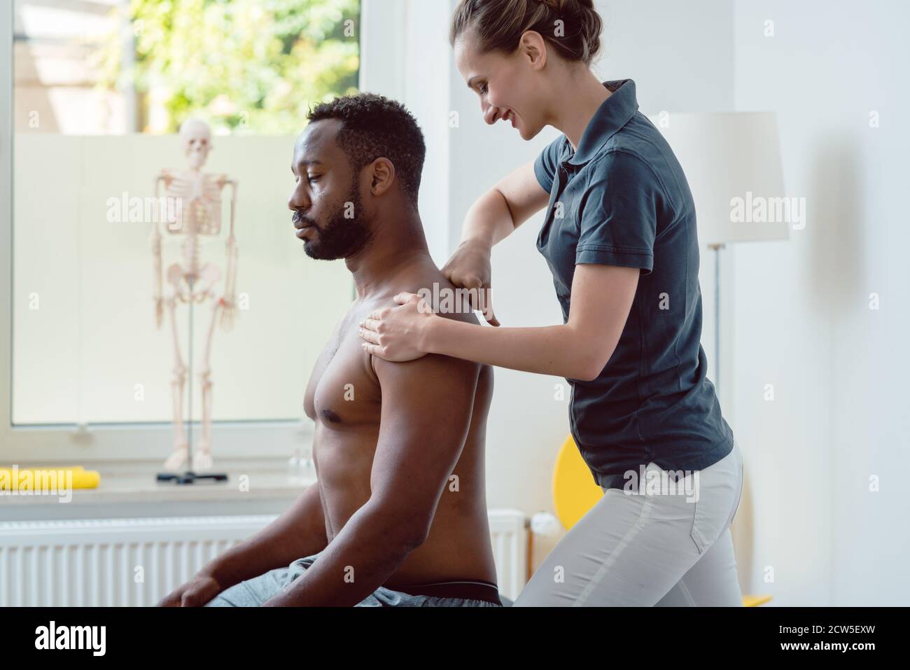 Physiotherapeuten massieren eine junge schwarze Mann auf die Schulter Stockfoto