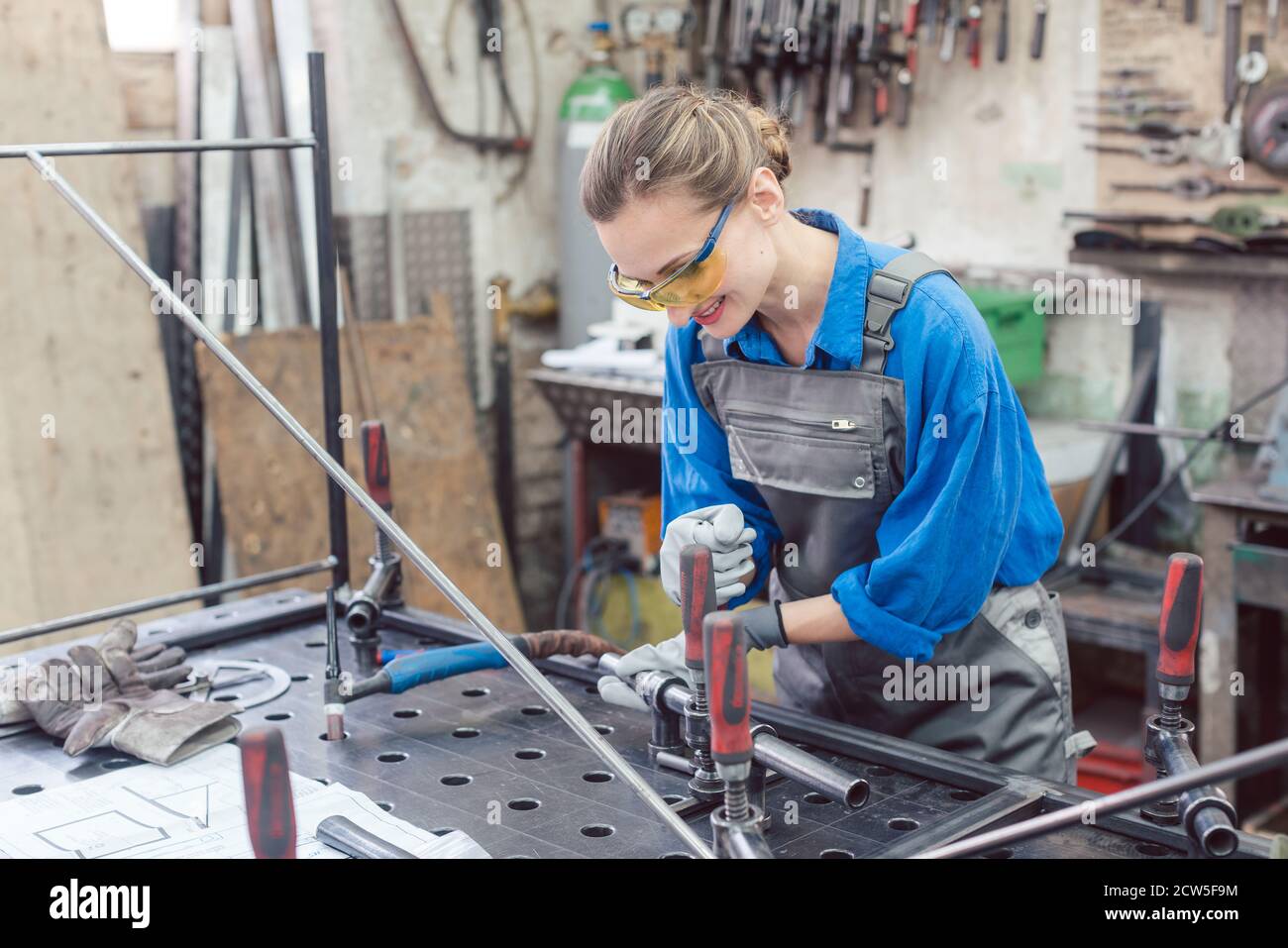 Frau in der Metallwerkstatt mit Werkzeug und Werkstück Stockfoto