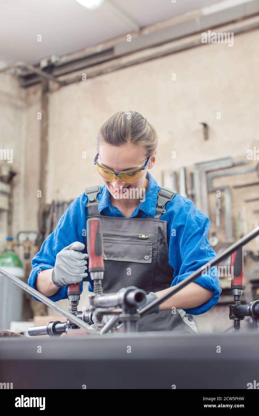 Frau in der Metallwerkstatt mit Werkzeug und Werkstück Stockfoto