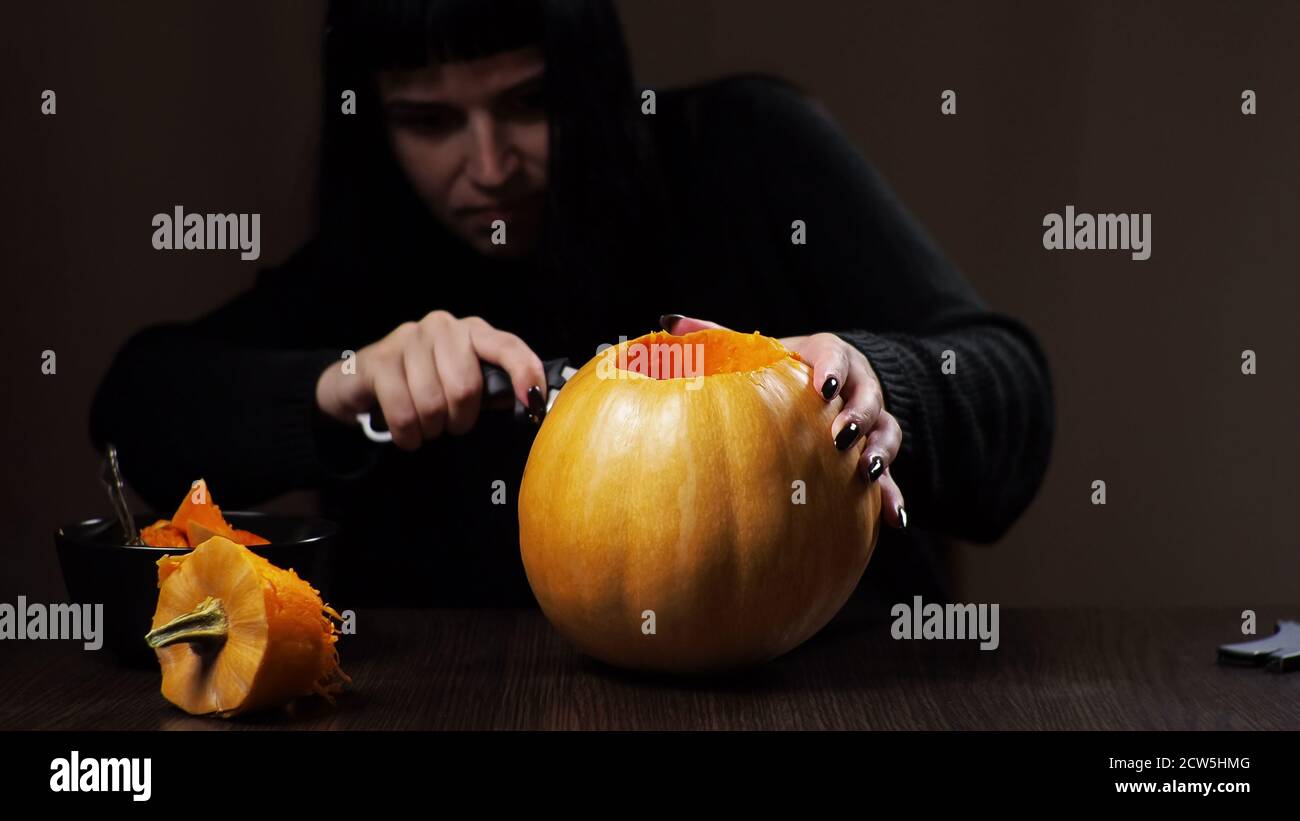 Junge Brünette Frau schnitzt einen Kürbis für Halloween Vorbereitung Stockfoto