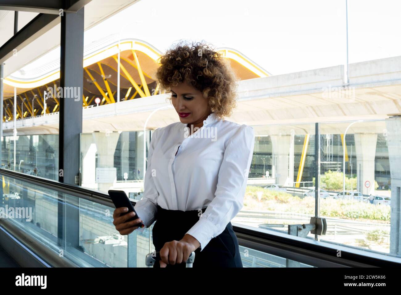 Stewardess mit ihrem Koffer mit ihrem Smartphone Stockfoto