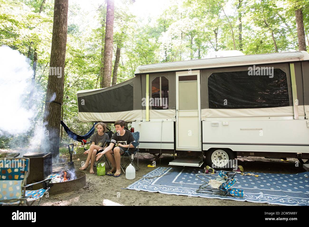 Weitansicht von Geschwistern rösten Hot Dog sitzen in Front Des Campers Stockfoto