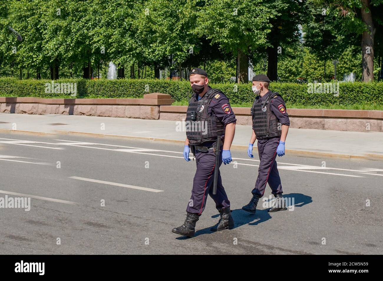 Zwei bewaffnete Bodyguards in schwarzen Uniformen, Schutzmasken, Handschuhe patrouillieren Stadtstraßen während der globalen Pandemie.Urban Ordnung Überwachung. Stockfoto