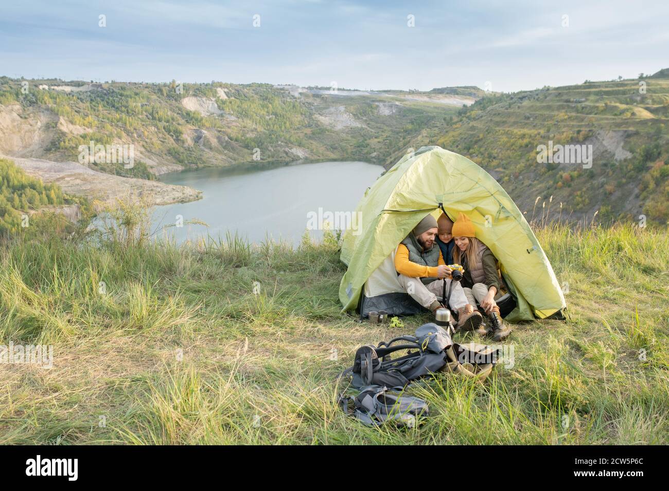 Junger Mann mit Fotokamera, der seinem kleinen Sohn Fotos zeigt Und Frau im Zelt Stockfoto