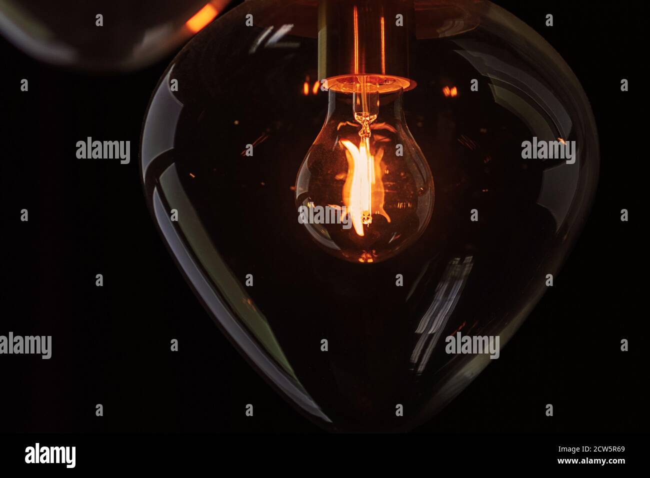 Glühbirne, die im Dunkeln in durchsichtigem Glasglobus leuchtet Stockfoto