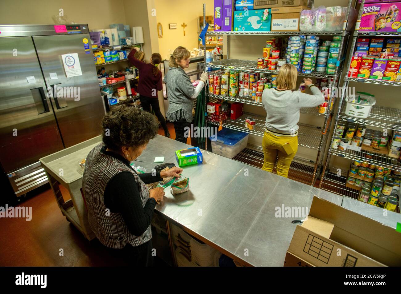 Kaukasische und afroamerikanische Freiwillige in der Wohltätigkeitsküche einer katholischen Kirche in Südkalifornien organisieren Lebensmittelspenden. Stockfoto