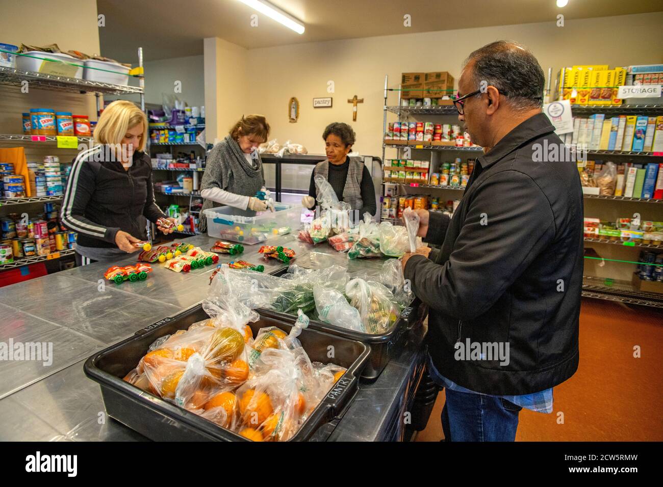 Spanische, kaukasische und afroamerikanische Freiwillige in der Wohltätigkeitsküche einer katholischen Kirche in Südkalifornien organisieren Lebensmittelspenden. Stockfoto