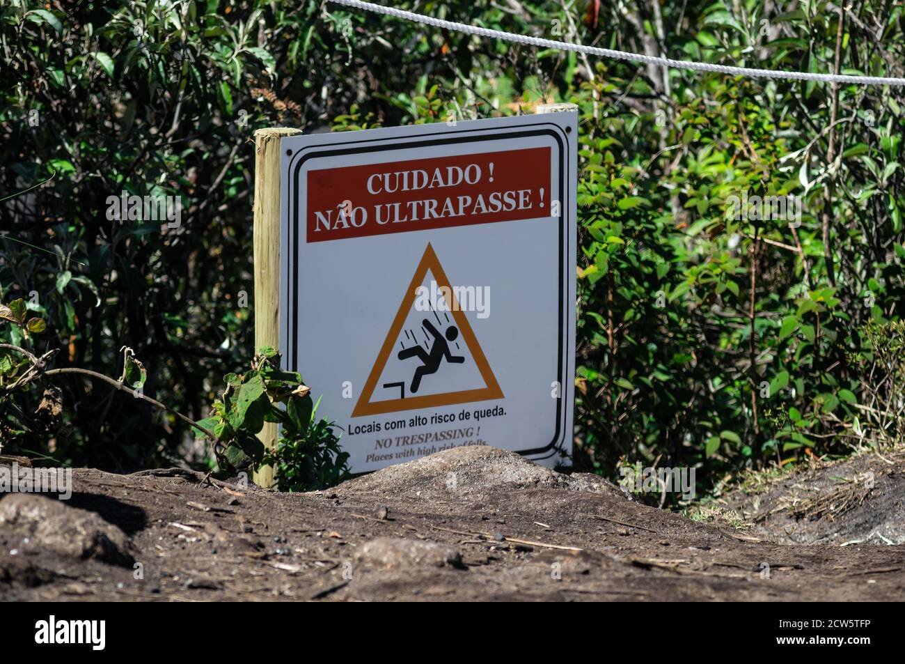 Ein Warnschild an einem Seilzaun, auf dem Besucher gebeten werden, den sicheren Bereich nicht zu betreten, da die Gefahr besteht, auf dem Gipfel des Landmarke Pedra da Macela zu fallen. Stockfoto