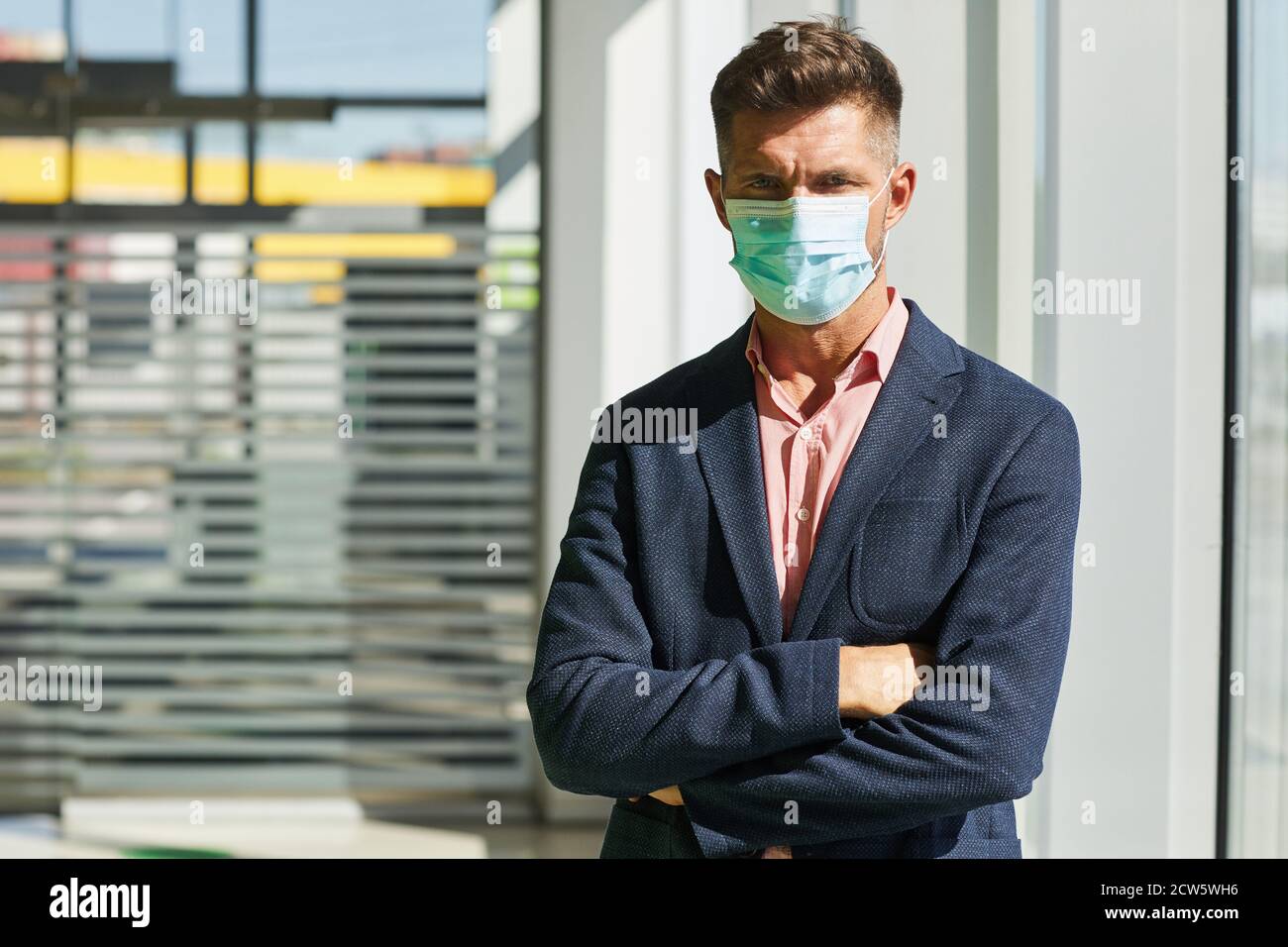 Waist up Porträt von schönen Geschäftsmann trägt Maske, während mit Armen im Sonnenlicht gekreuzt stehen, kopieren Raum Stockfoto