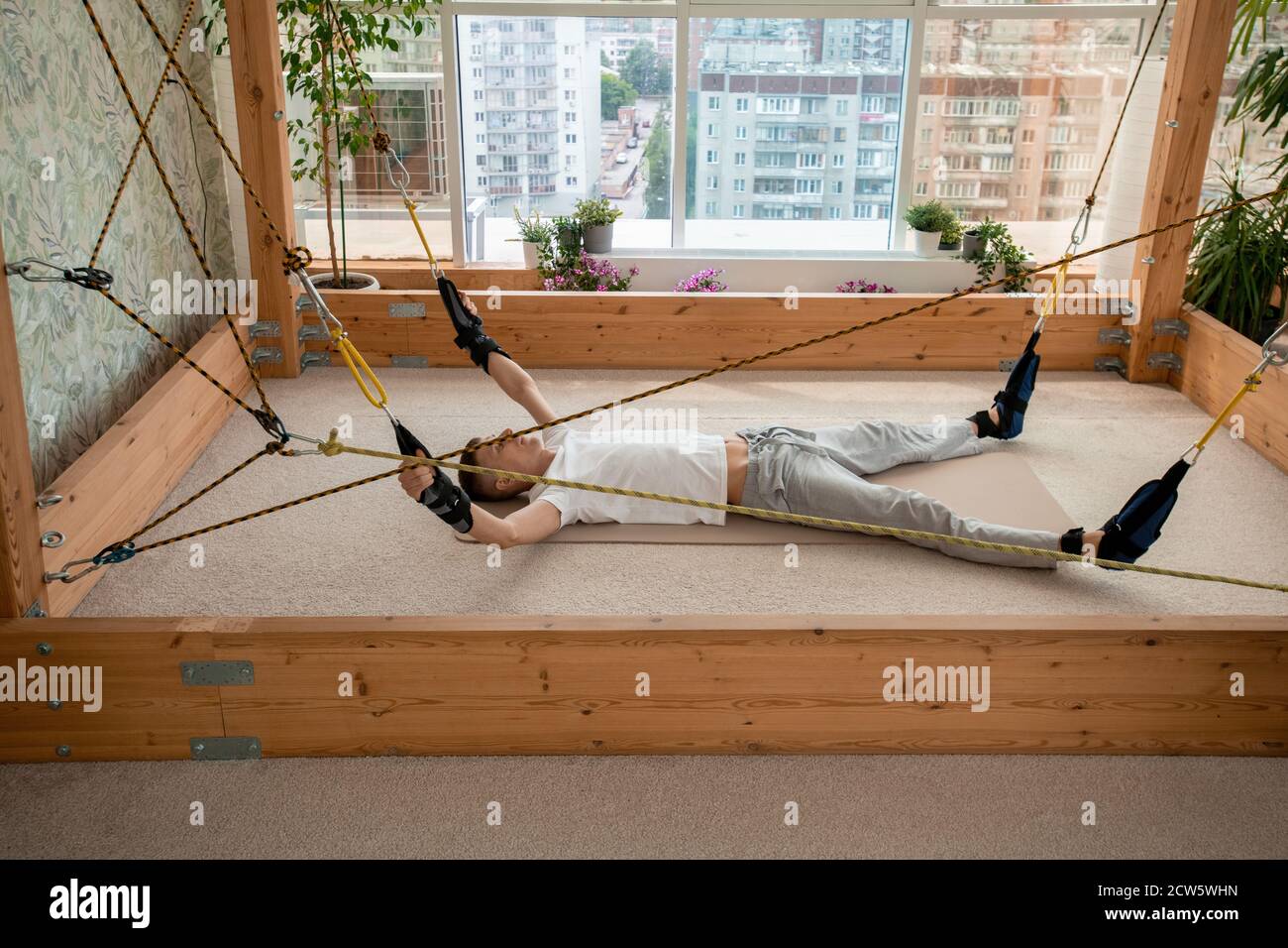 Junge Sportler in der aktiven auf Matte liegend innerhalb rechteckigen Holz Struktur Stockfoto