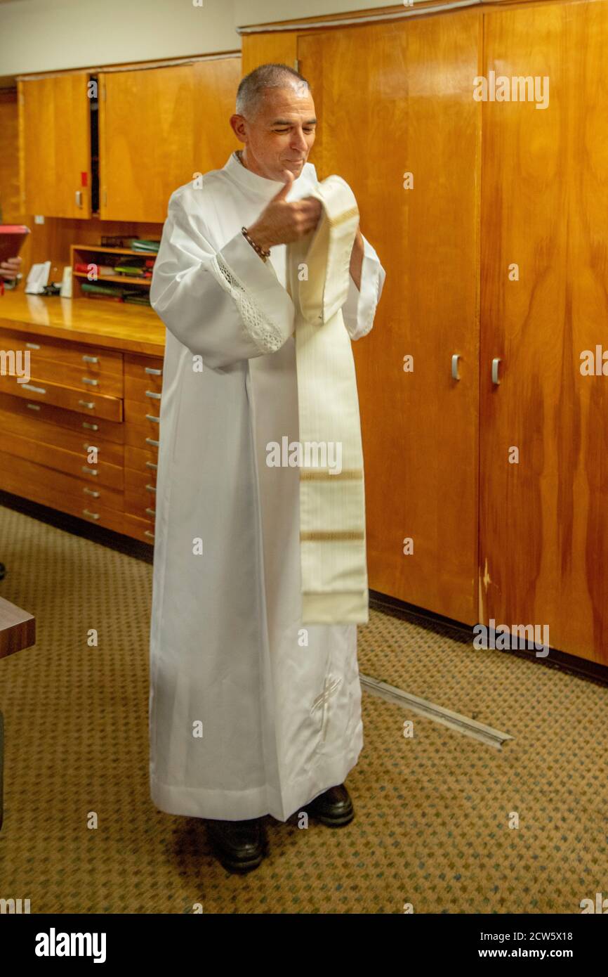 Der Diakon einer katholischen Kirche in Südkalifornien dons seine Gewänder vor der Messe. Stockfoto