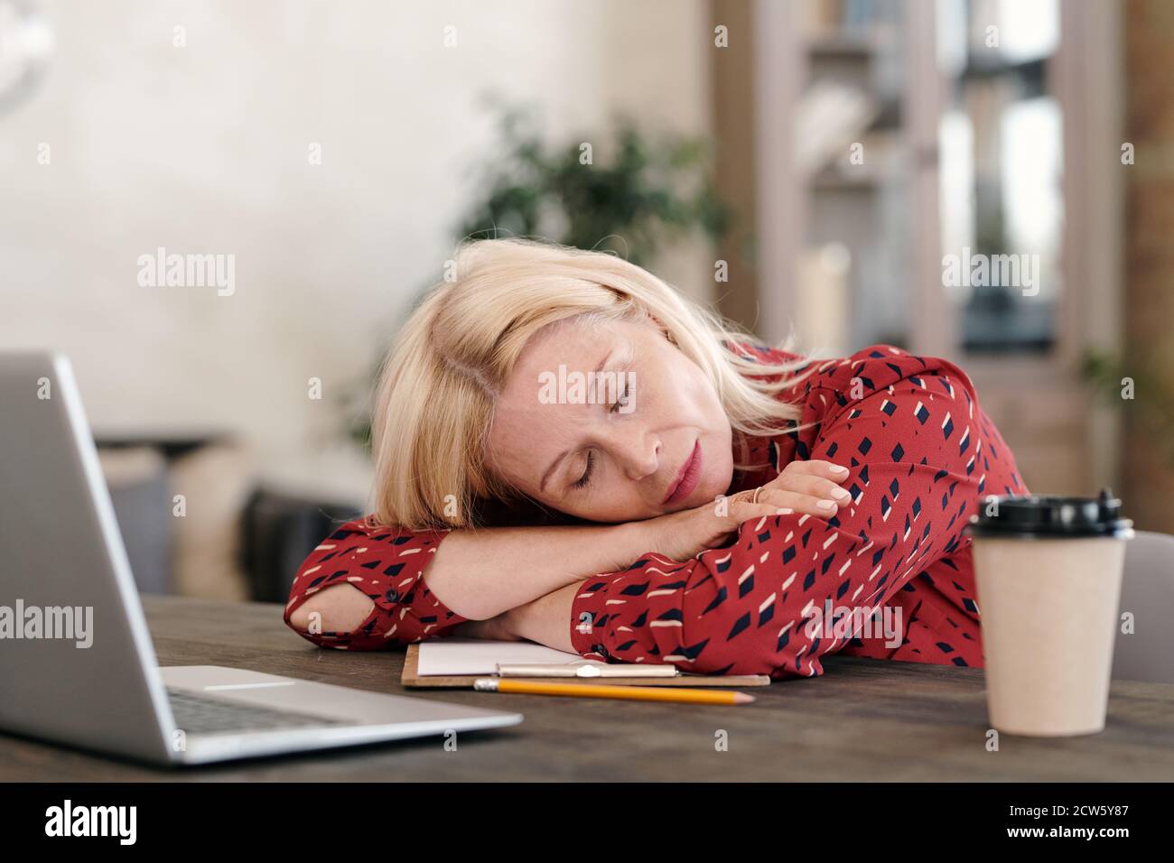 Überarbeitete reife Geschäftsfrau in formalwear halten ihren Kopf auf den Armen Stockfoto